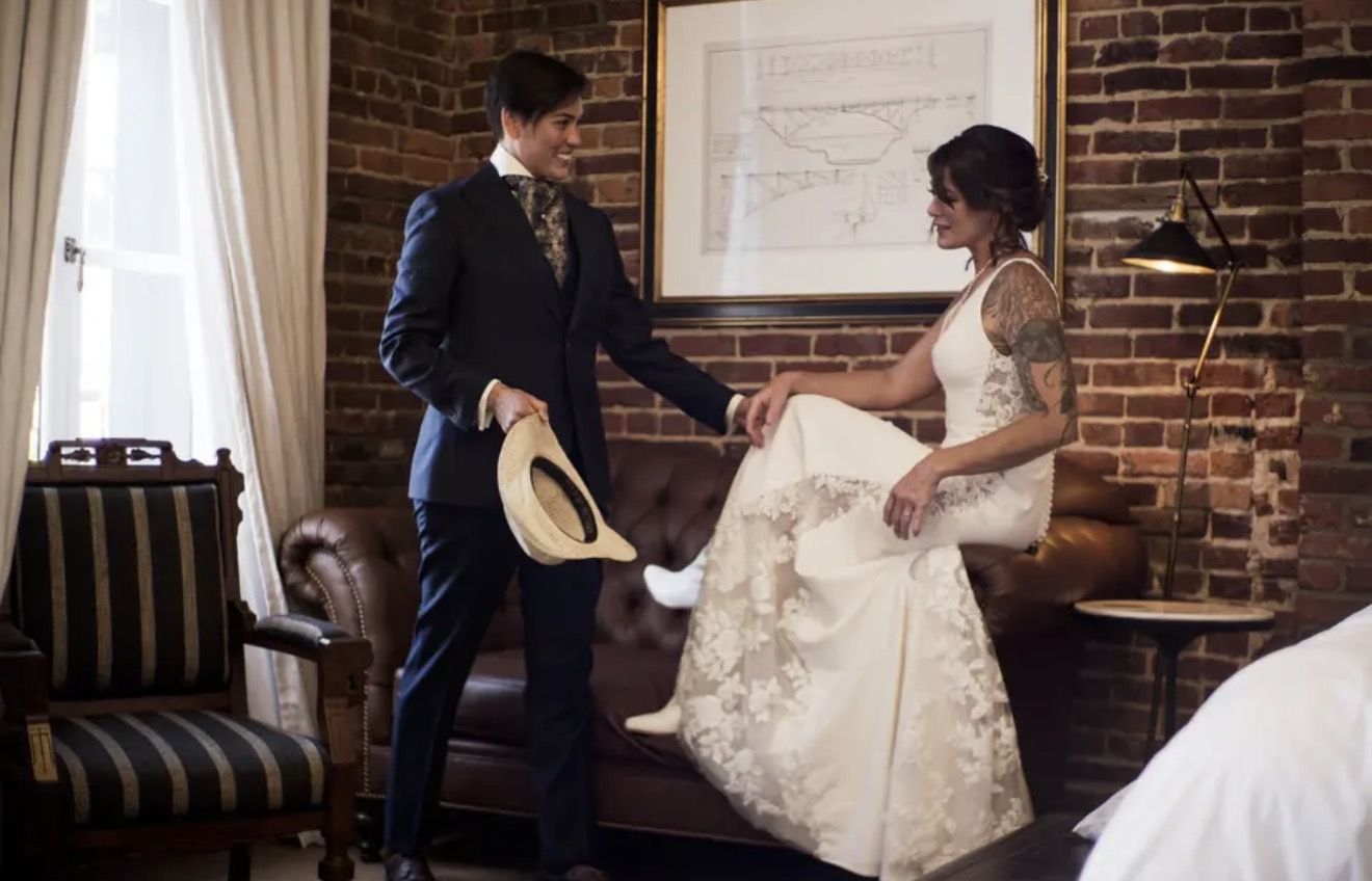 A bride and groom in a brick-walled hotel room before the ceremony