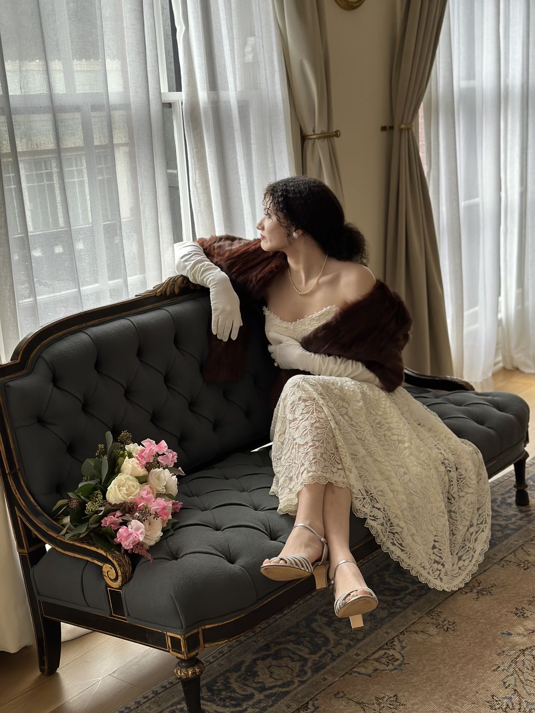 A bride reclining on a velvet settee by a bright window